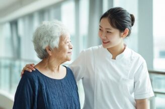 Pflegefachkraft begleitet eine ältere Patientin im hellen Krankenhaus